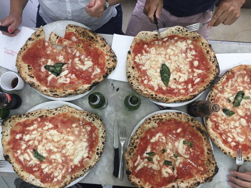 Bird's-eye view of five large margherita pizzas on a table before and after consumption