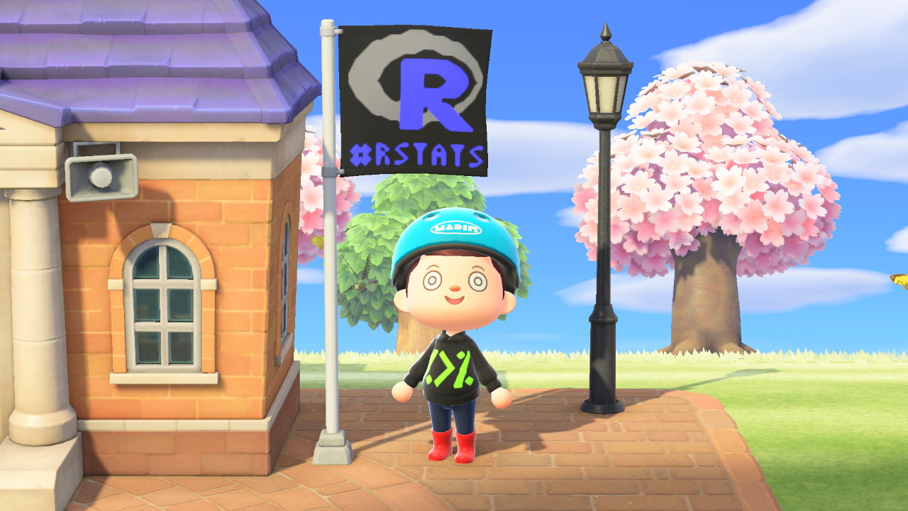 An Animal Crossing villager stands in front of the town flag, which has the R logo on it.